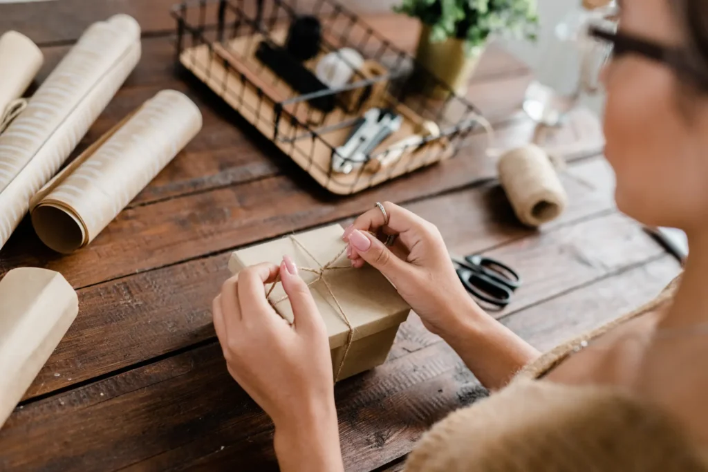 Mains ficelant un colis sur une table en bois