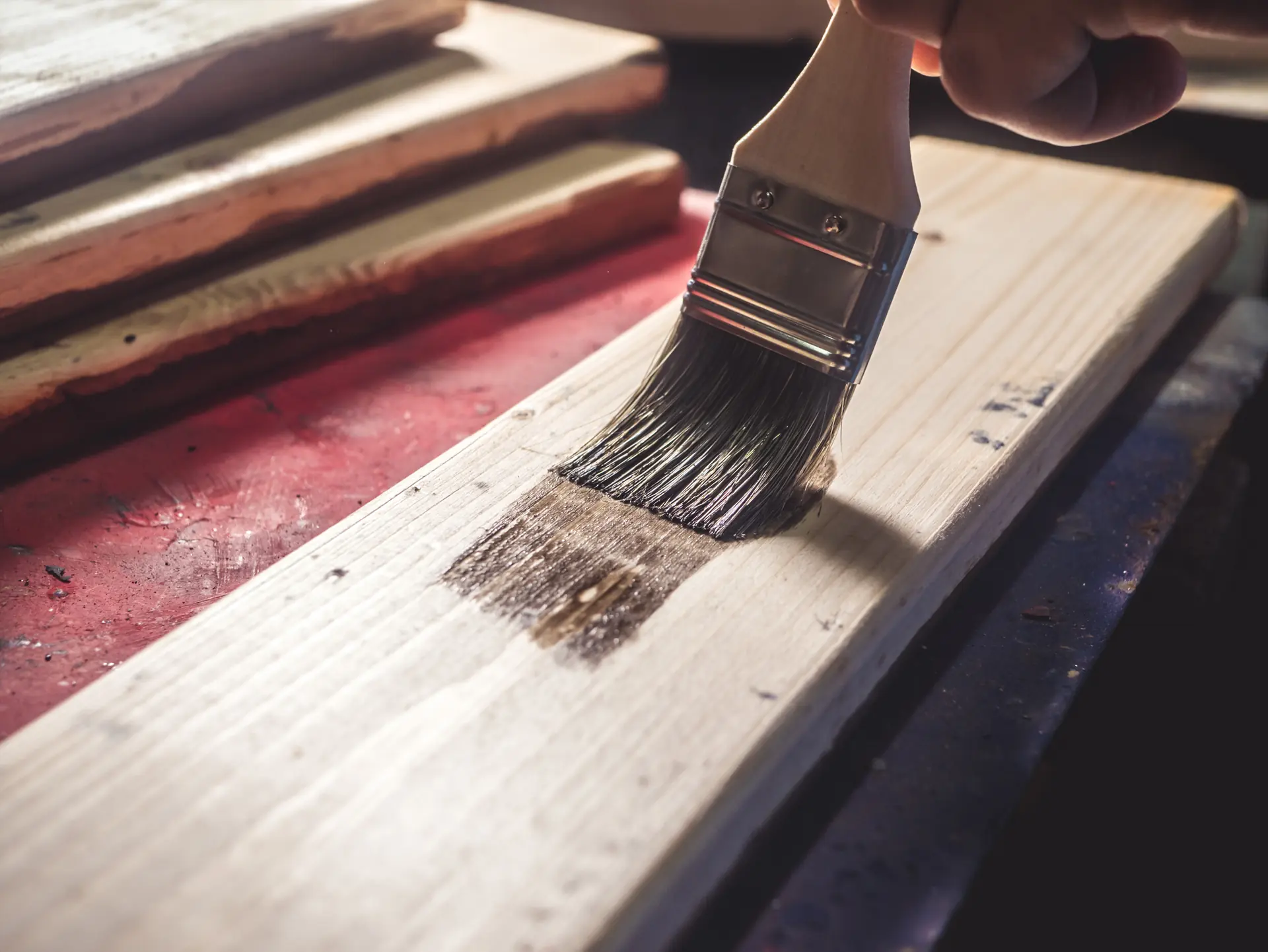 Pinceau appliquant une lasure sur une planche de bois