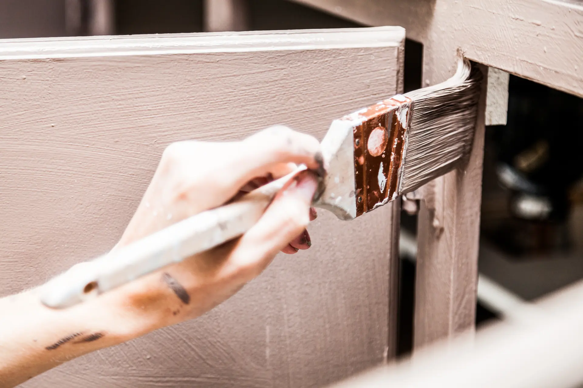 Main appliquant de la peinture au pinceau sur une armoire