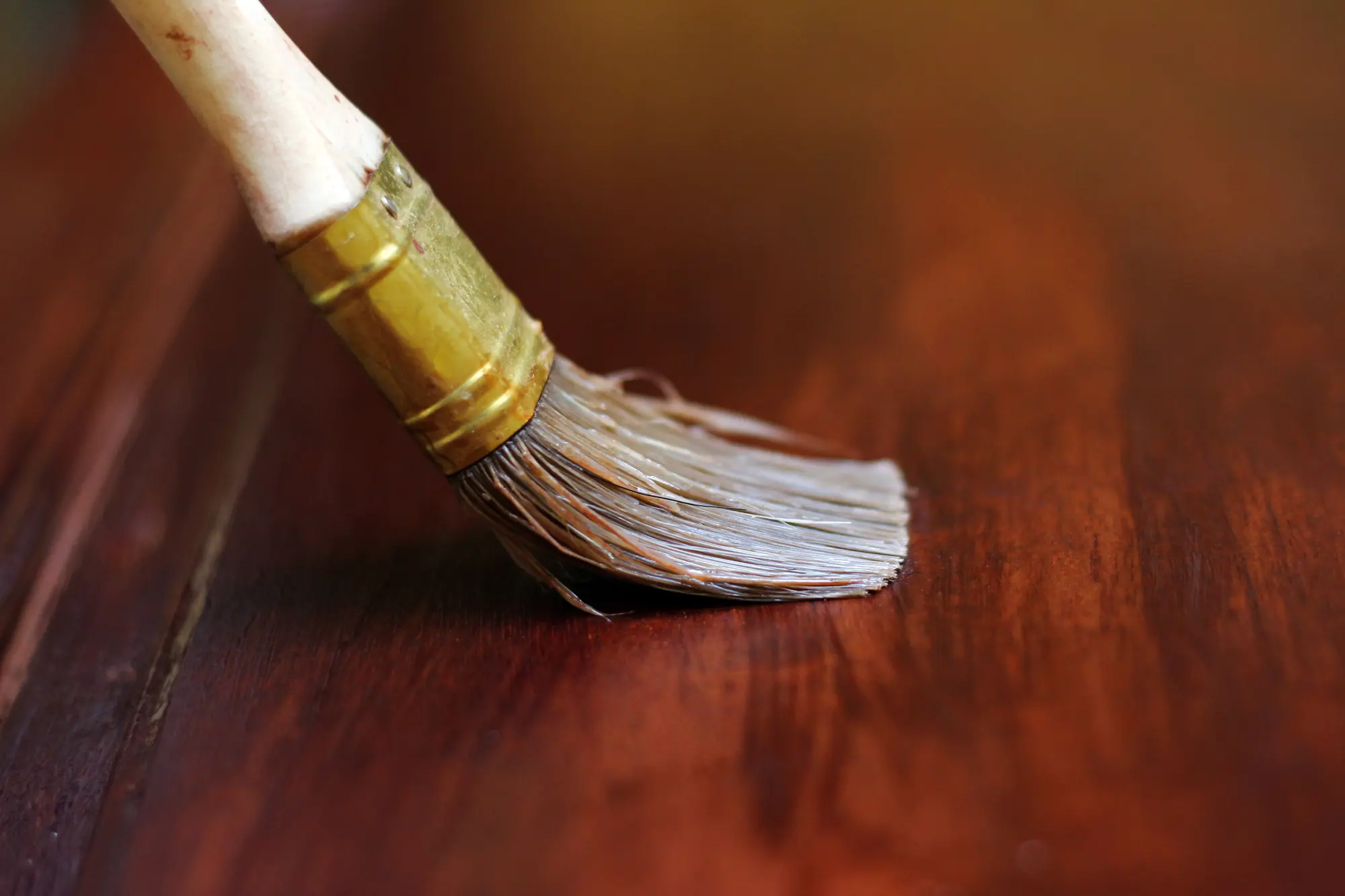 Pinceau appliquant une lasure sur une surface en bois