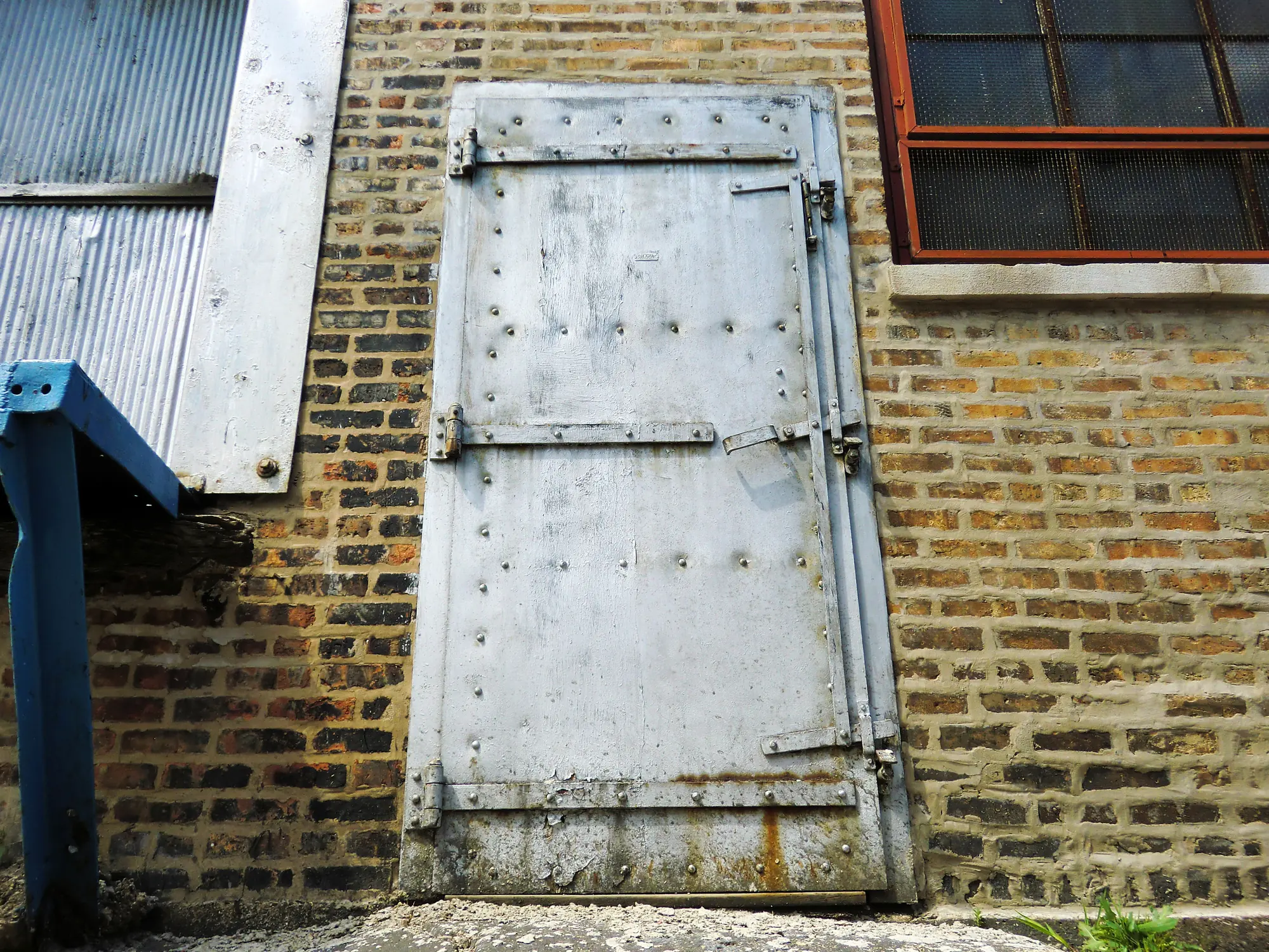 Porte métallique industrielle devant un mur de briques